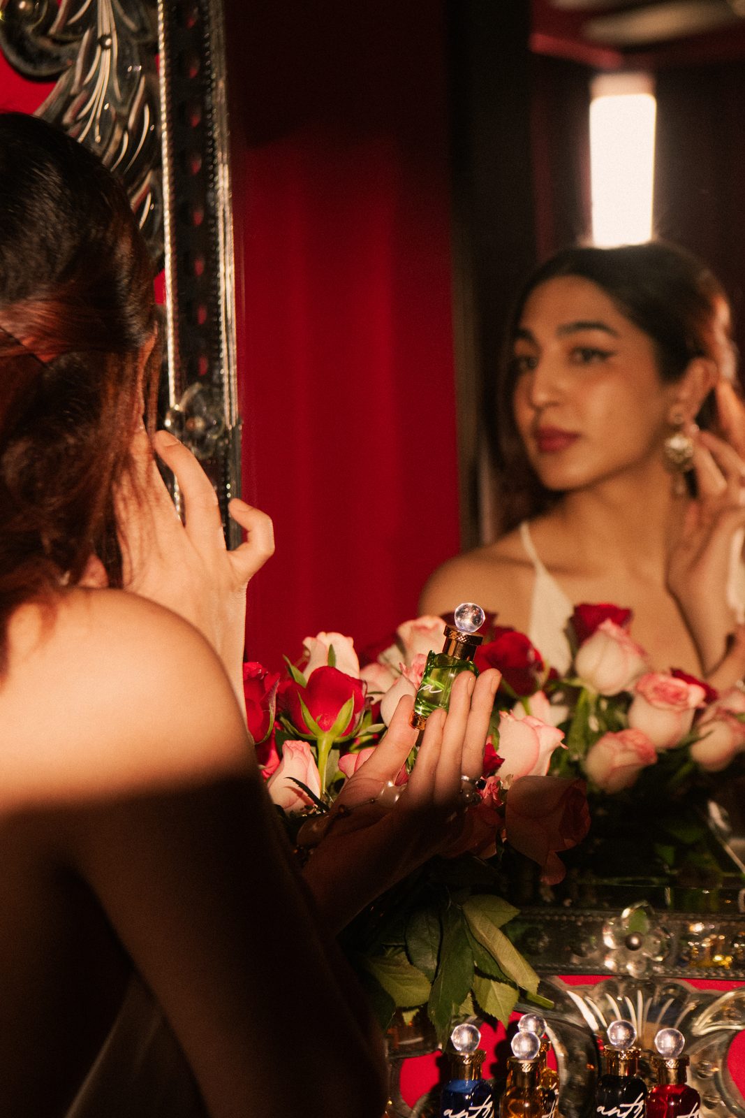 A woman anoints herself at a candlelit vanity